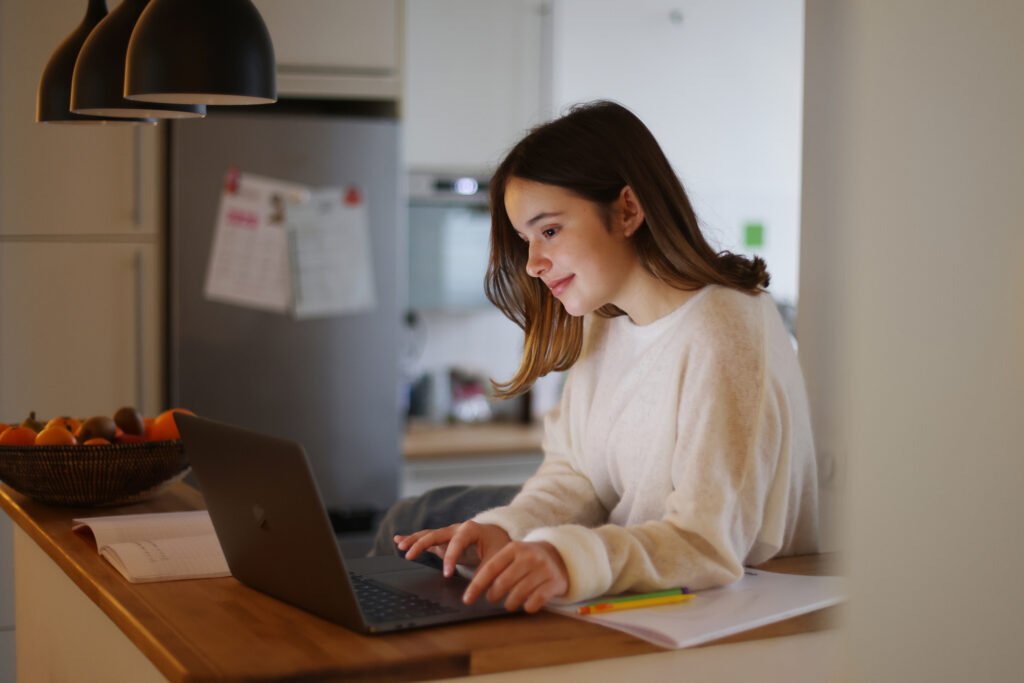 An image displaying a girl who's studying using her laptop at home.