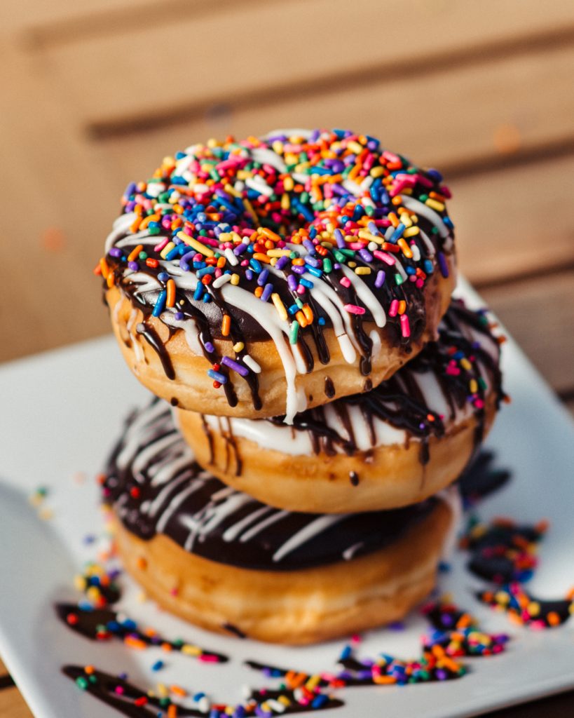 stack of 3 sprinkled chocolate doughnuts