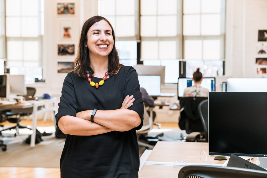 woman standing and grinning at her desk in the office