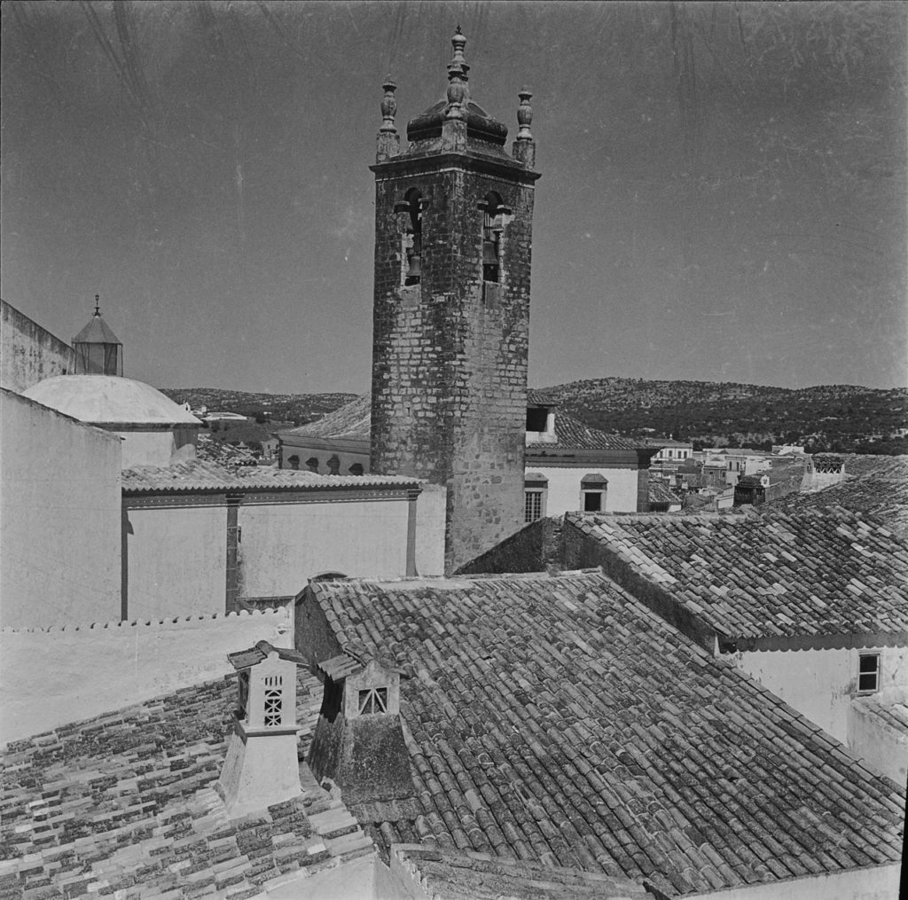 black and white photo of stone buildings and thatched roofs