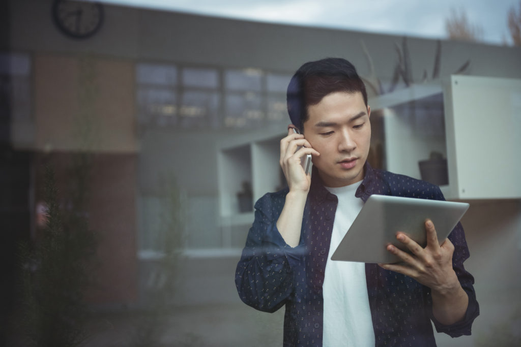 man on phone looking at tablet