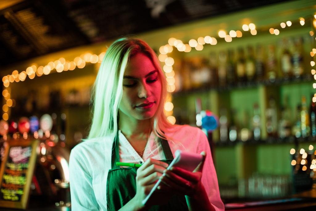 waitress writing order in front of a bar