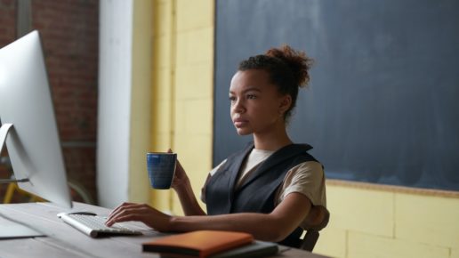 teacher on computer in front of blackboard