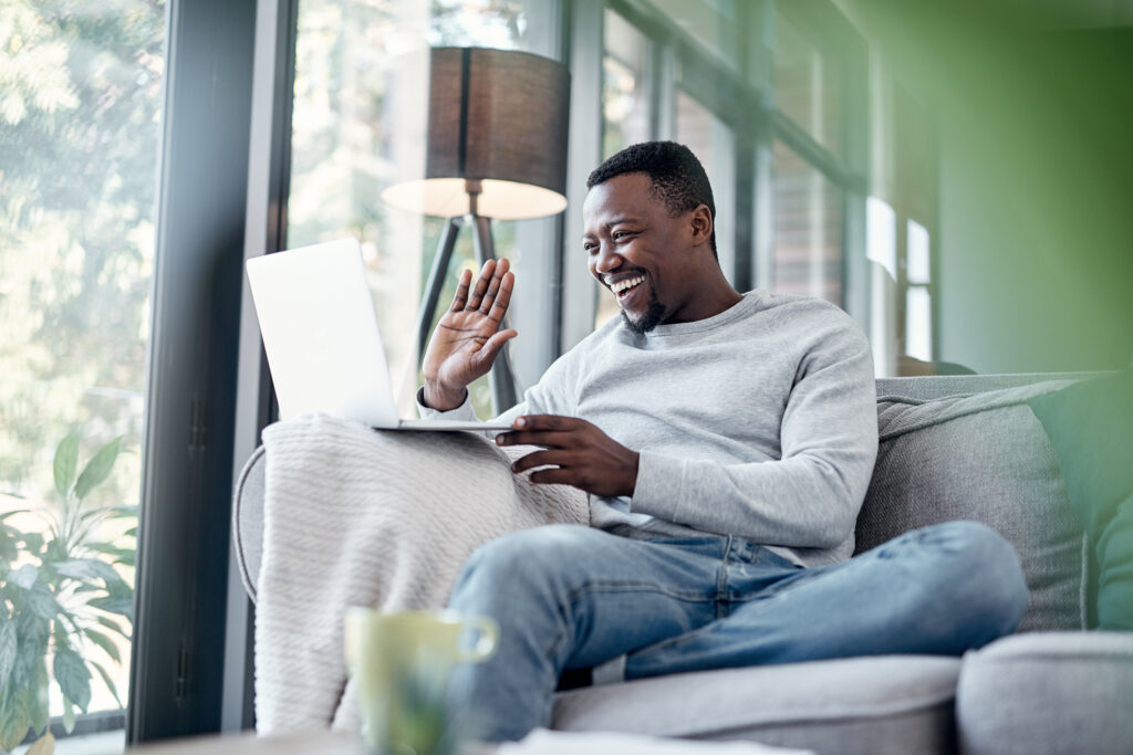 Shot of a young man using a laptop to make a video call on the sofa at home