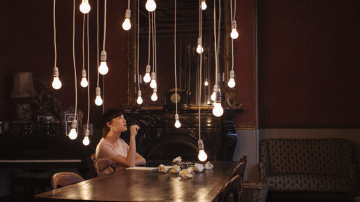 Woman sitting at table with hanging lightbulbs