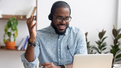 Smiling African American employee in headphones using laptop