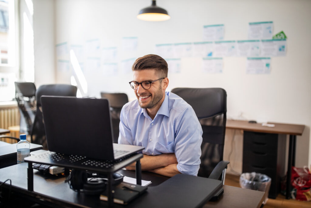 Businessman sitting at his desk smiling during an online training in office. Young man on a video conference meeting at office.