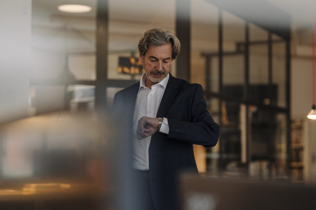 Senior businessman checking the time in office