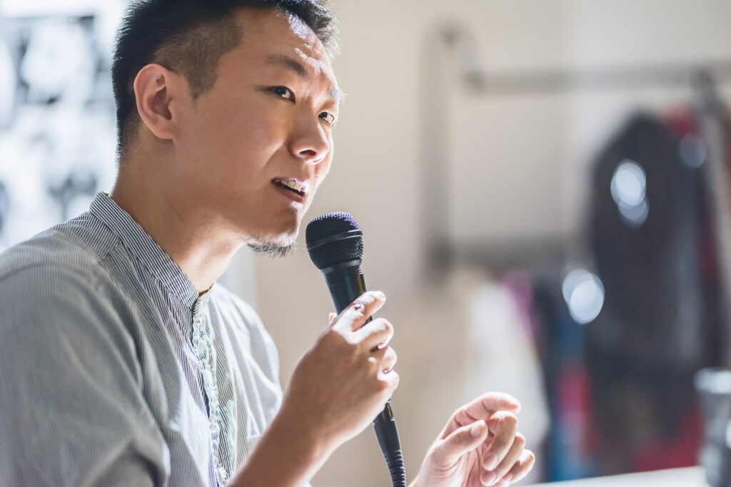 man speaks into microphone to deliver a presentation