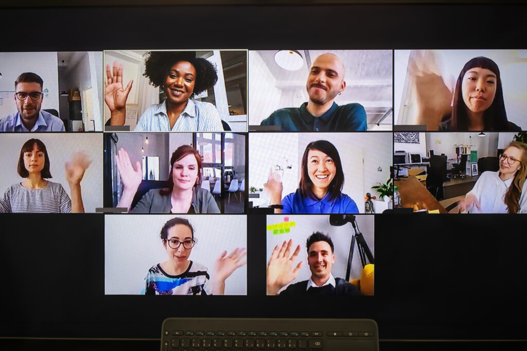Desktop computer screen with people waving during online meeting