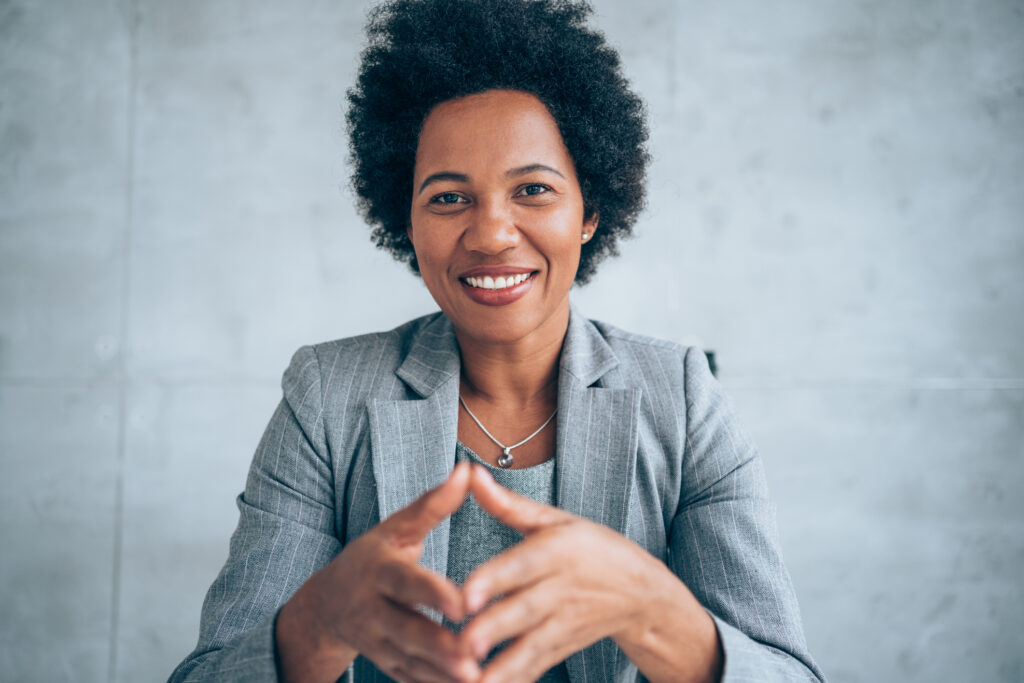 woman folds hands and makes eye contact with computer camera