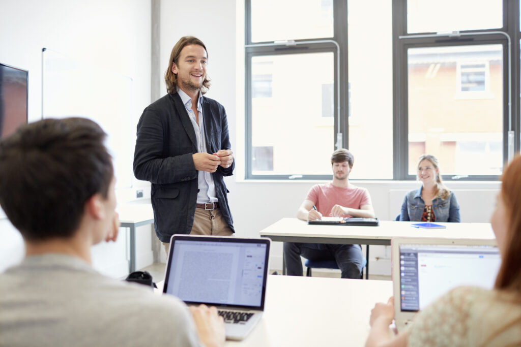 A man in front of a class presenting a multimedia presentation.