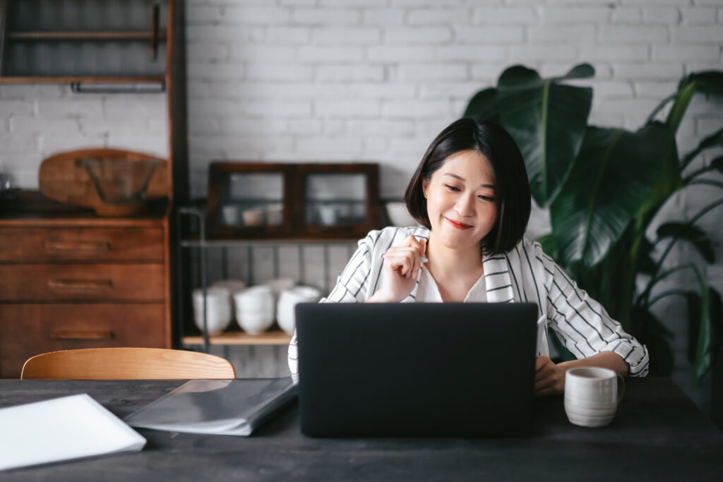 Woman having online business meeting, video conferencing on laptop with her business partners, working from home in the living room