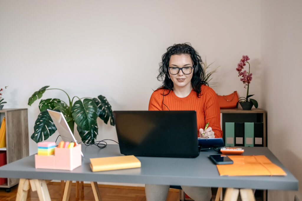 Happy young woman with glasses at work. Using laptop for watching a demonstration speech.