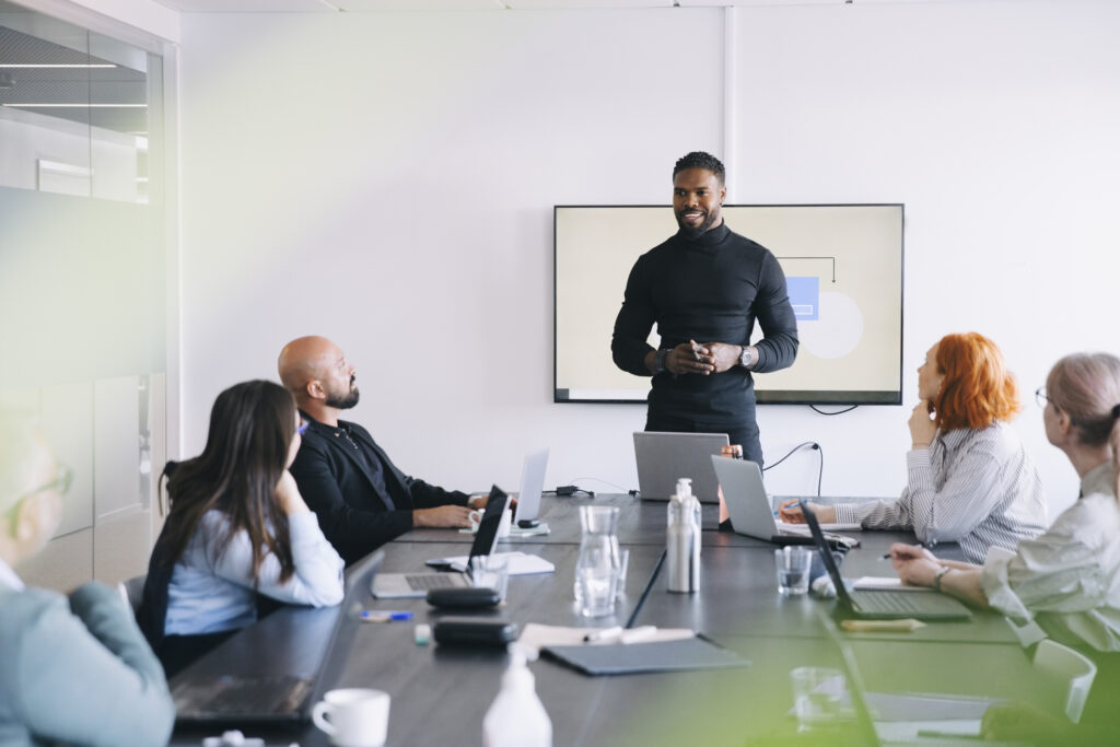 Male professional sharing business strategies with colleagues in board room