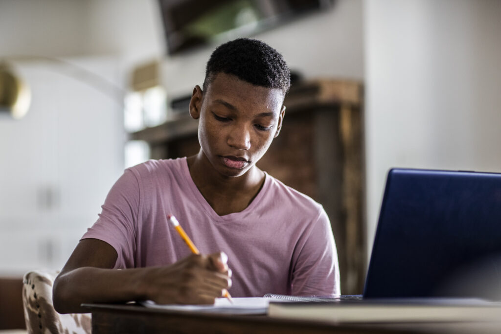 Teenage boy doing schoolwork at home.