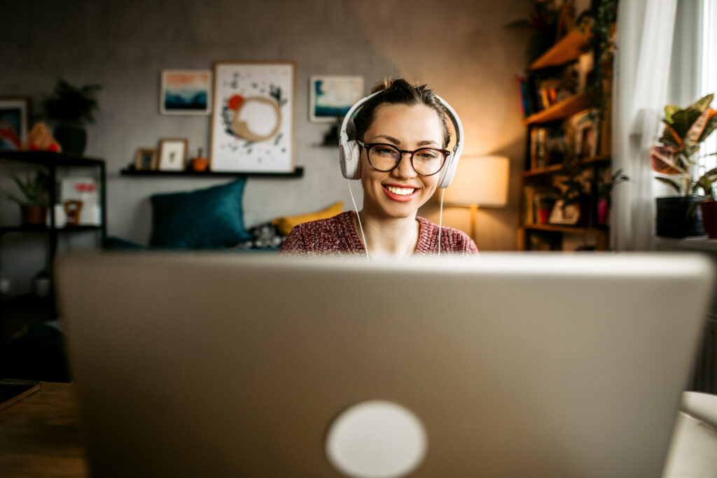 Young woman teaching online from her living room. Young woman wearing headphones while having a online training at home.