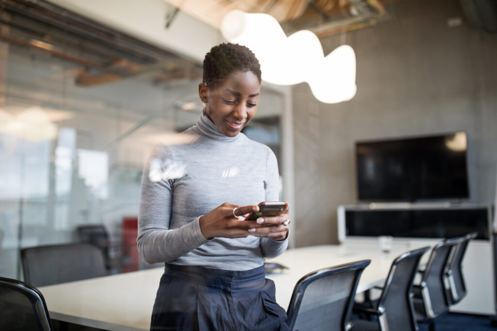 Mature female professional standing in conference room and reading the meeting agenda on her phone.