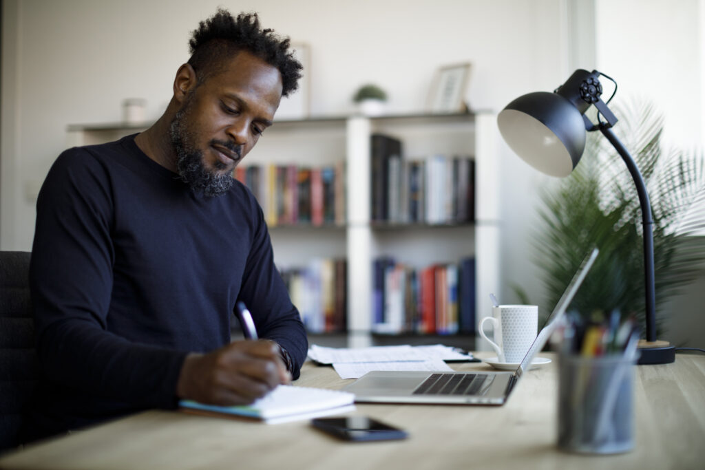 Adult male creating a meeting agenda at home