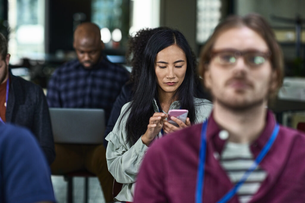 Businesswoman checking her smartphone at a team meeting.