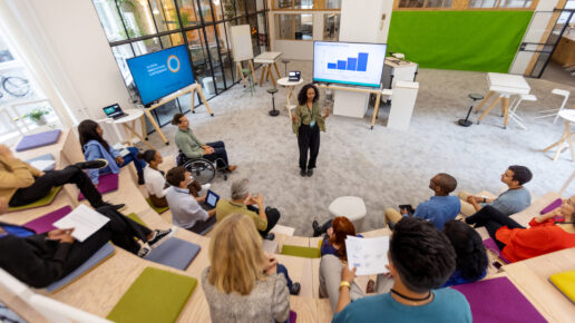 African woman giving speech to group of business people during startup launch event. Multiracial business professionals sitting at seminar hall and listening to young entrepreneur.