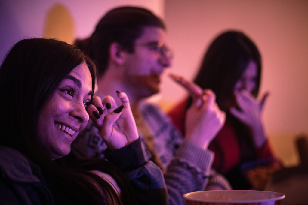 Group of young friends, two women and one man, having PowerPoint night gathering at home with snacks.