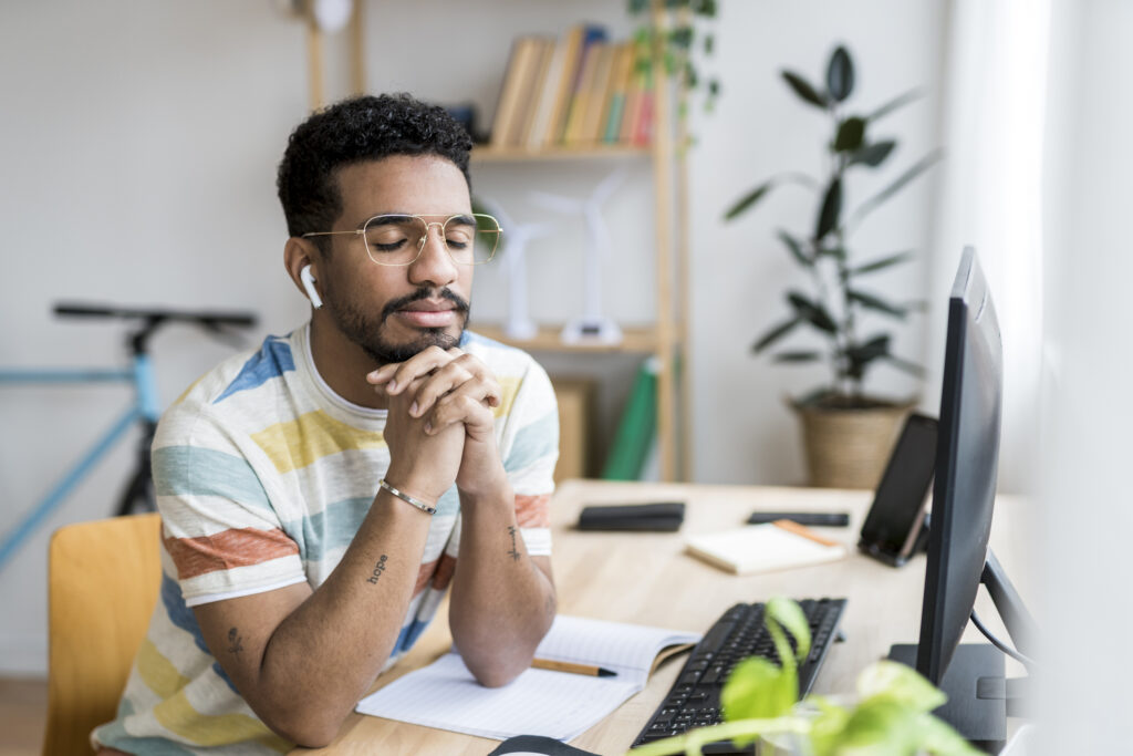 Young entrepreneur thinking with eyes closed at the desk.