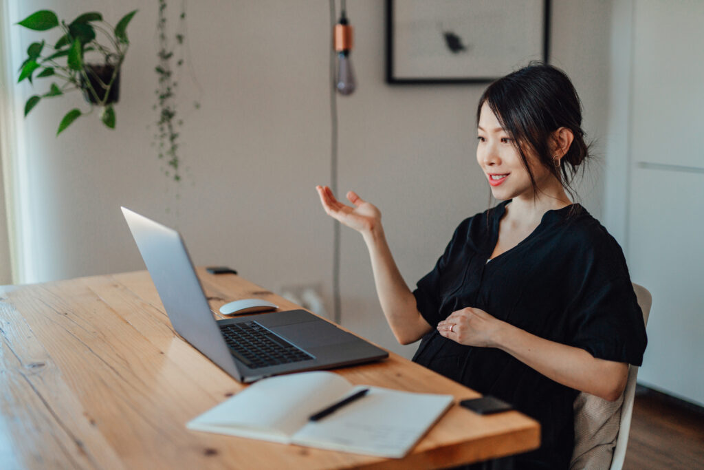 Professional and beautiful young Asian woman having a presentation over video call using laptop in the living room. Mother working from home.