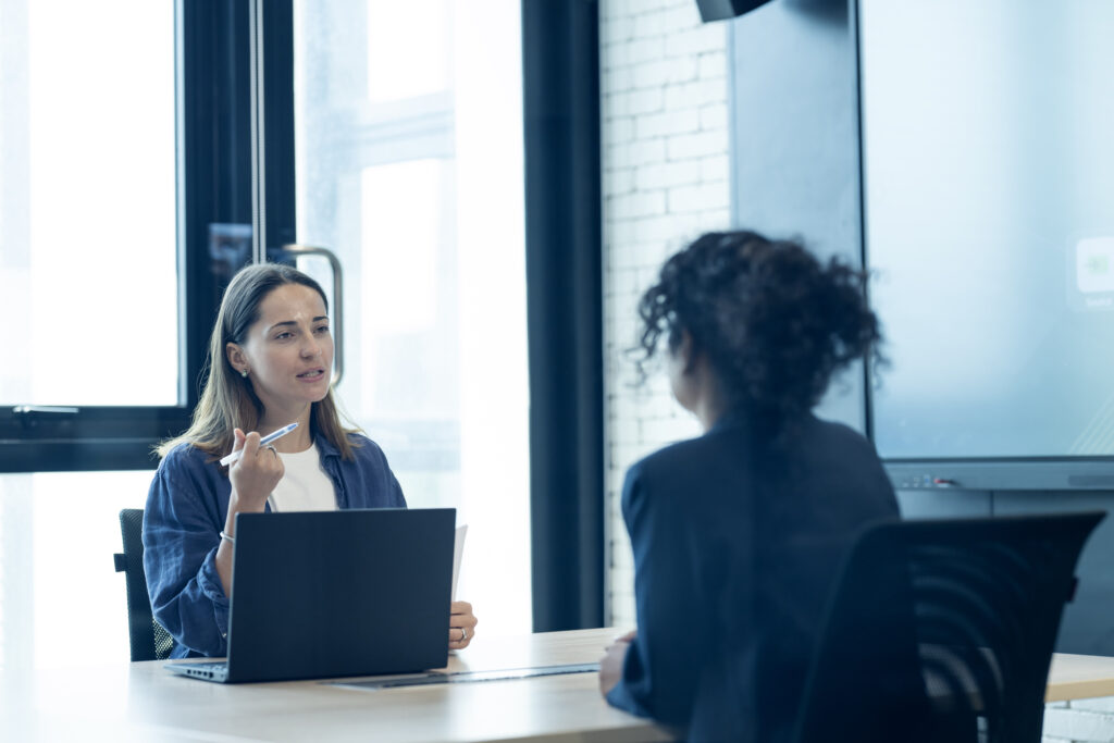 Forecast future talent needs with strategic workforce planning. HR manager conducting an interview and considering women for a new hire in a meeting room of a modern business office.