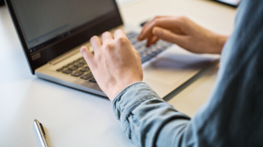 Close up of female hand using laptop on office table. Cropped shot of businesswoman working on laptop.