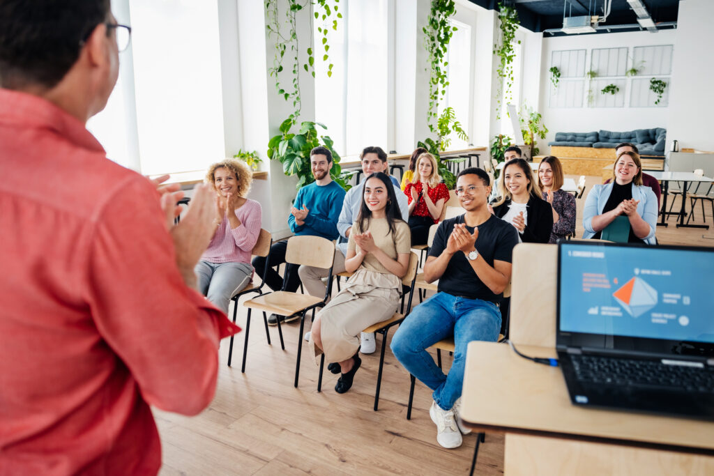 An audience sitting down and applauding the host after watching a presentation together during a seminar session.